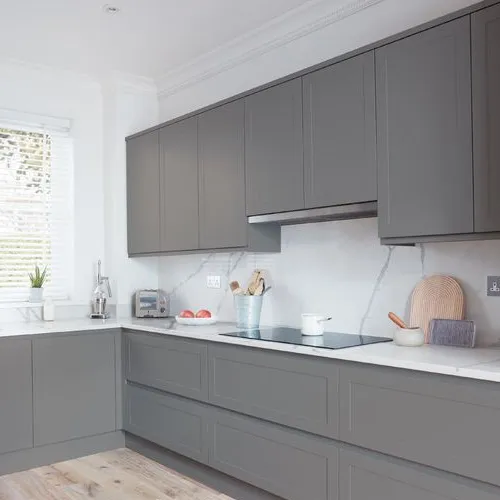 Compact L-shaped kitchen in grey with slab doors and a marble-effect splashback