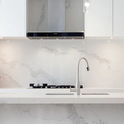 Contemporary kitchen with a marble-effect worktop running up the splashback, a gooseneck tap and a stainless canopy hood