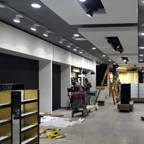 Retail interior during a shopfitting installation, with display units, bulkheads and track lighting going in